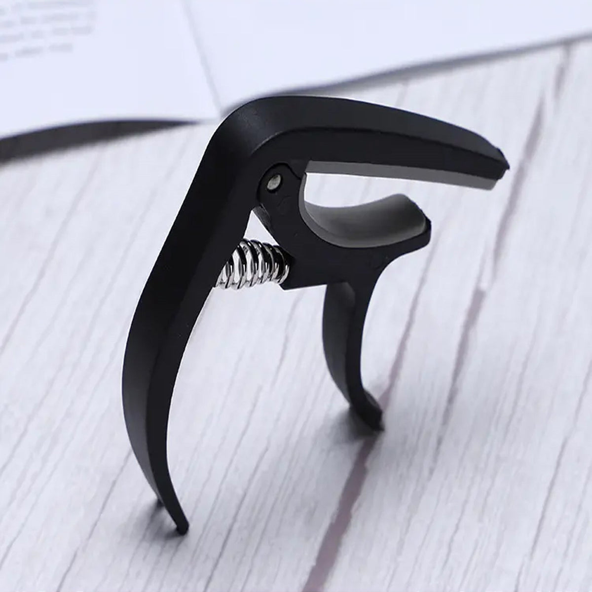 Guitar capo and pick holder positioned on a guitar neck, ready for playing.